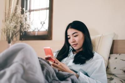 Woman in bed looking at her phone